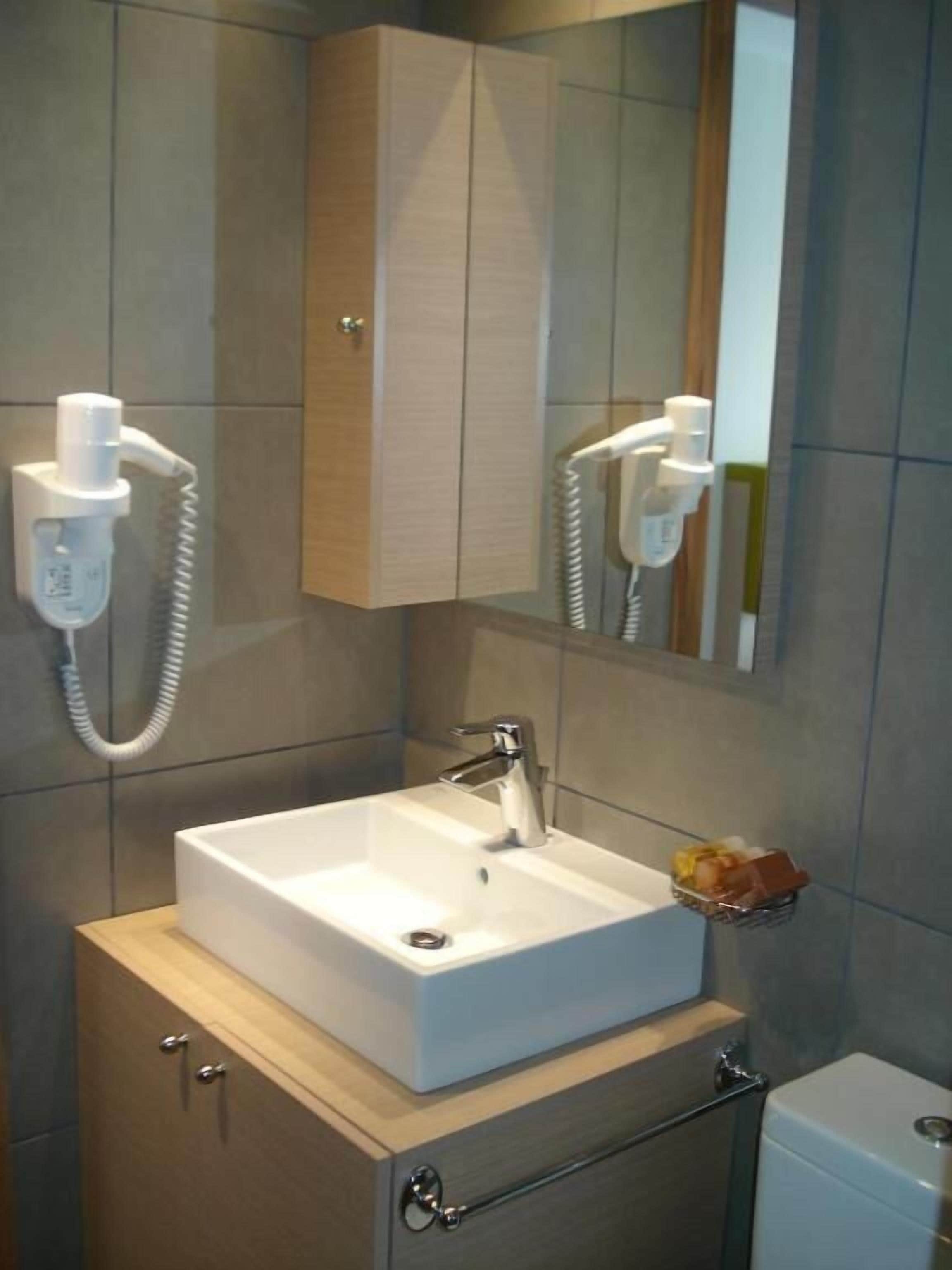 A bathroom with a white sink, a mirror, and a towel rack.