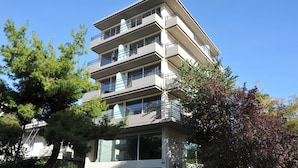 A multi-story building with balconies and large windows, surrounded by trees. - Elements Rooms and Apartments (Chalandri)