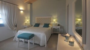 Un dormitorio con una cama grande, mesitas de noche, un espejo y dos velas encendidas.
