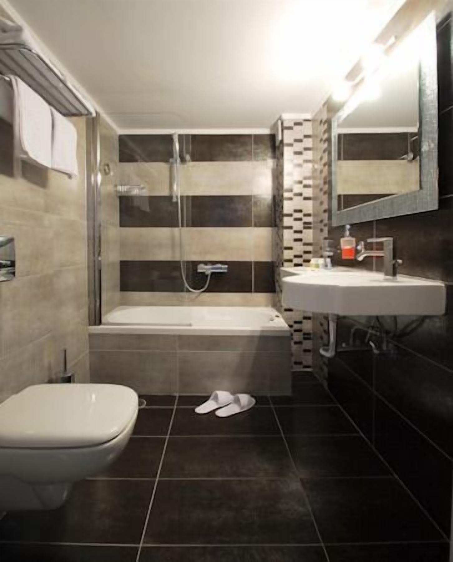 A modern bathroom with a bathtub, toilet, and sink.