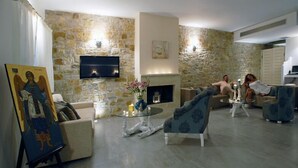Una sala de estar con paredes de piedra, un televisor de pantalla plana, una chimenea y muebles modernos.