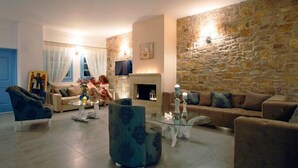 Un salón acogedor con pared de piedra, chimenea y asientos cómodos.