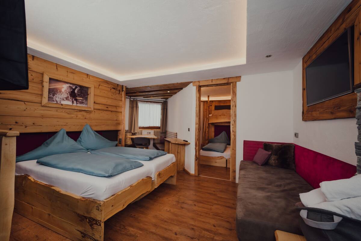 Ein Zimmer mit Holzboden, zwei Betten, einem Schreibtisch und einem Sofa.
