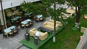 An outdoor seating area with tables and chairs, surrounded by greenery and trees. - Hotel Siret Mamaia (Constanta)