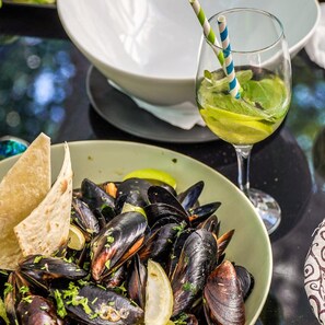 A bowl of mussels with lemon and herbs, a glass of drink with a straw, and a plate of flatbread. - Hotel Siret Mamaia (Constanta)