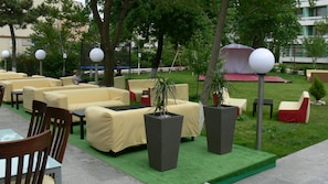 Outdoor seating with tables and chairs, surrounded by greenery and trees. - Hotel Siret Mamaia (Constanta)