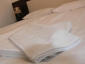 A neatly made bed with a folded white towel and a pillow. - Hotel Siret Mamaia (Constanta)