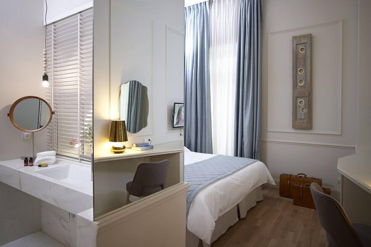 Hotellihuone, jossa on kylpyhuone, sänky, työpöytä ja peili.