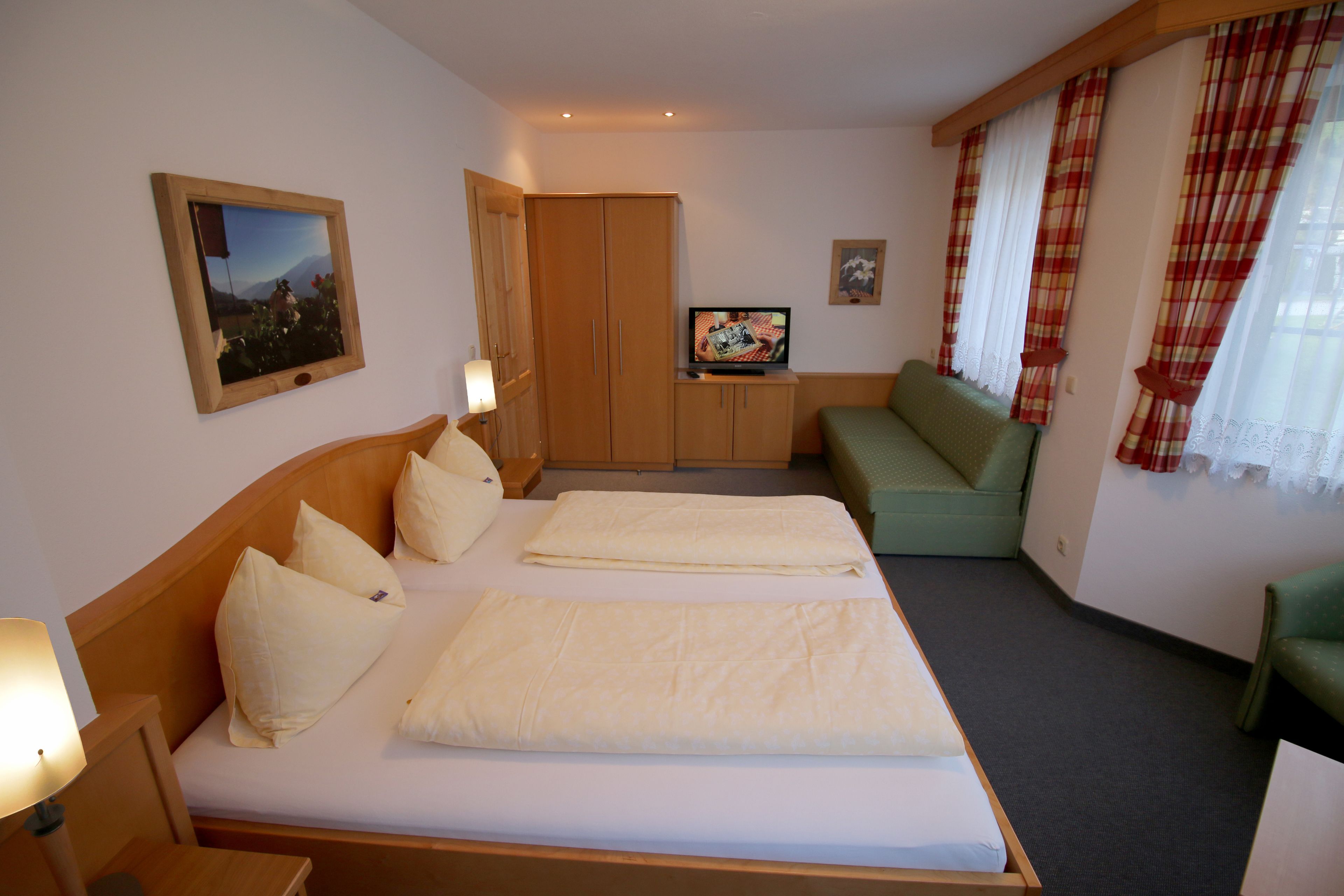 Habitación de hotel con dos camas, televisión, sofá y armario.