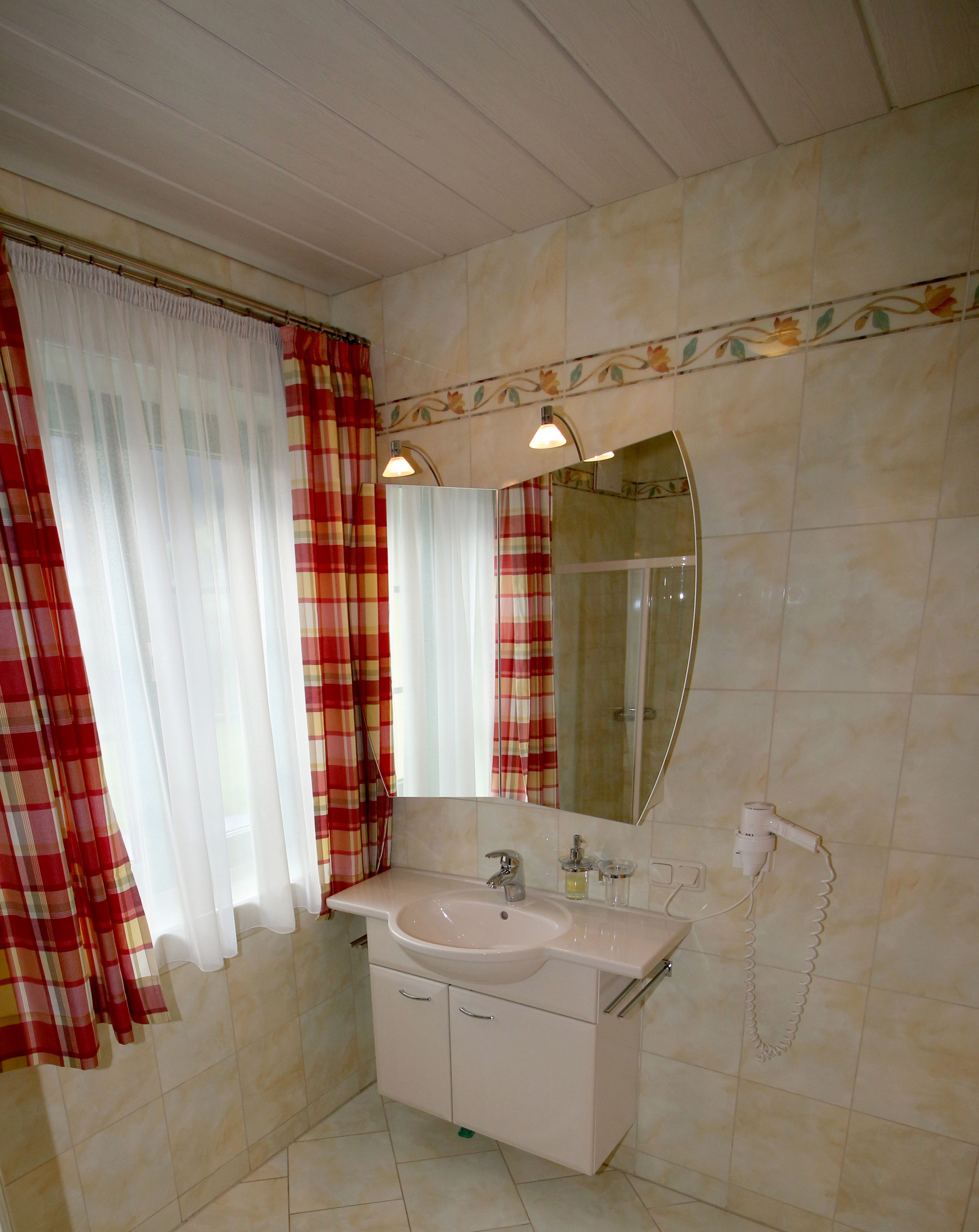 Ein Badezimmer mit Waschbecken, Spiegel und zwei Wandleuchten.
