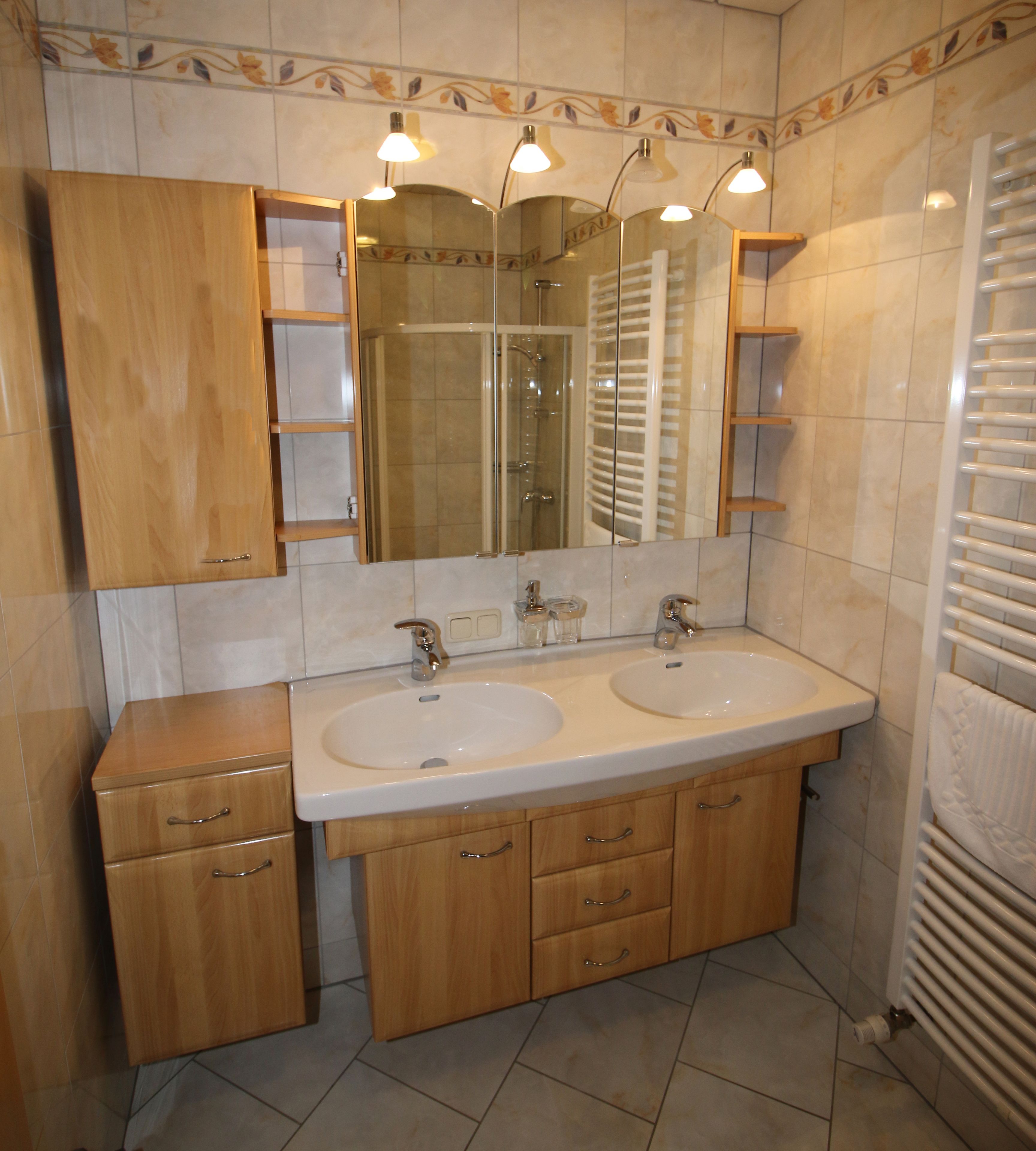 A bathroom with two sinks, a mirror, and a shower.