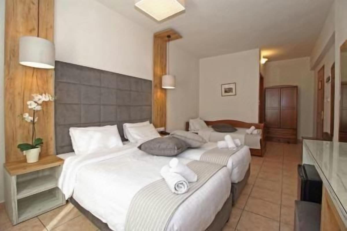 A hotel room with a large bed, bedside tables, a wardrobe, and a mirror.