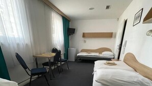 Habitación de hotel con dos camas, un escritorio, una silla, un televisor y una ventana con cortinas.