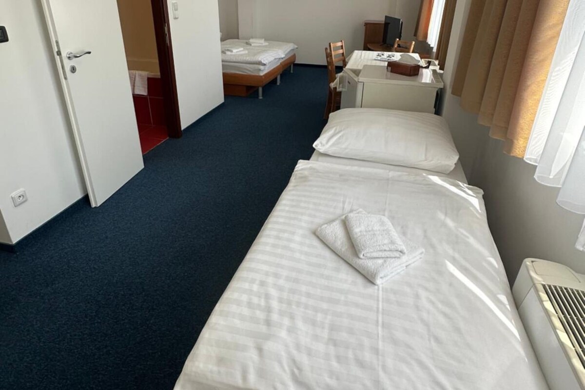 A hotel room with two beds, a desk, a chair, and a window with curtains.
