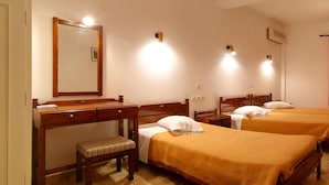Habitación de hotel con dos camas, un escritorio de madera, un banco y un espejo.