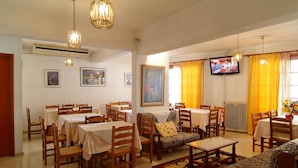 Un comedor con mesas y sillas, un sofá, un televisor y obras de arte en las paredes.