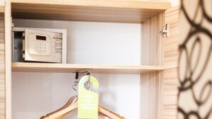 Un armario de madera con espacio para colgar, un microondas en la repisa superior, y un par de zapatillas y un cepillo en la repisa inferior.