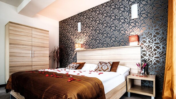 Un dormitorio moderno con una cama grande, una mesita de noche, un armario y un papel tapiz estampado.