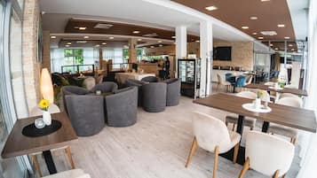 A modern interior with seating areas, tables, and a kitchen in the background.