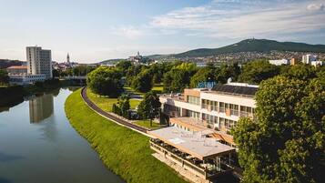 A riverside view of a modern building with a flat roof and a covered outdoor area.