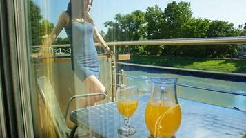 A woman in a dress standing by a railing with a table that has two glasses and a pitcher of orange juice.