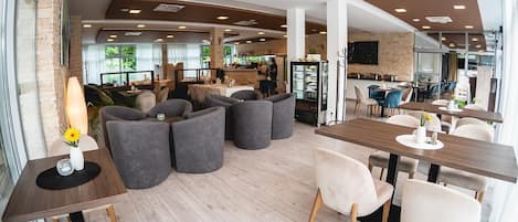 A modern interior with seating areas, tables, and a kitchen in the background.