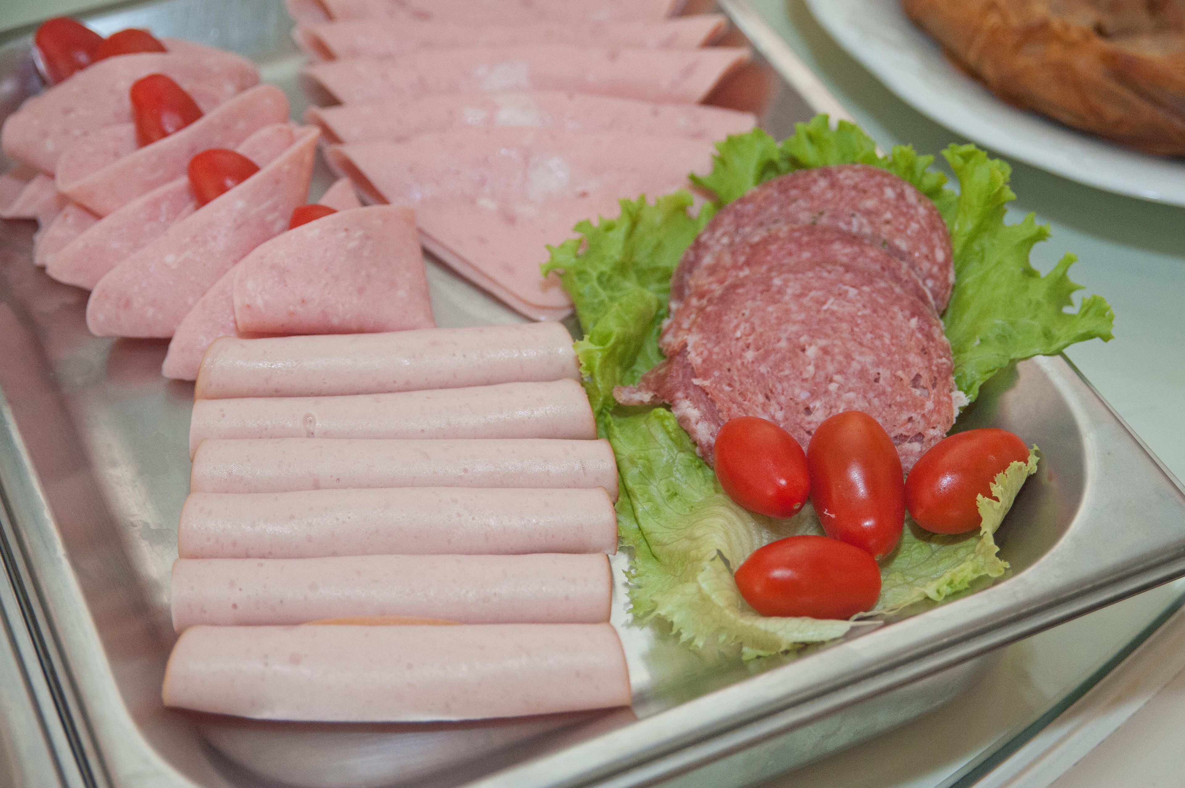 A variety of sliced meats and vegetables on a tray.