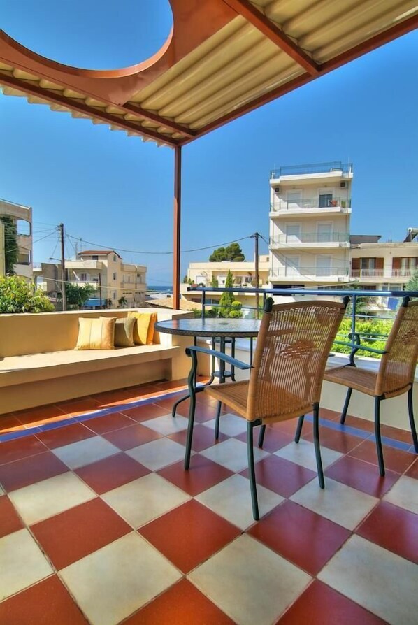 Une terrasse avec un sol à carreaux, une table et deux chaises en osier.