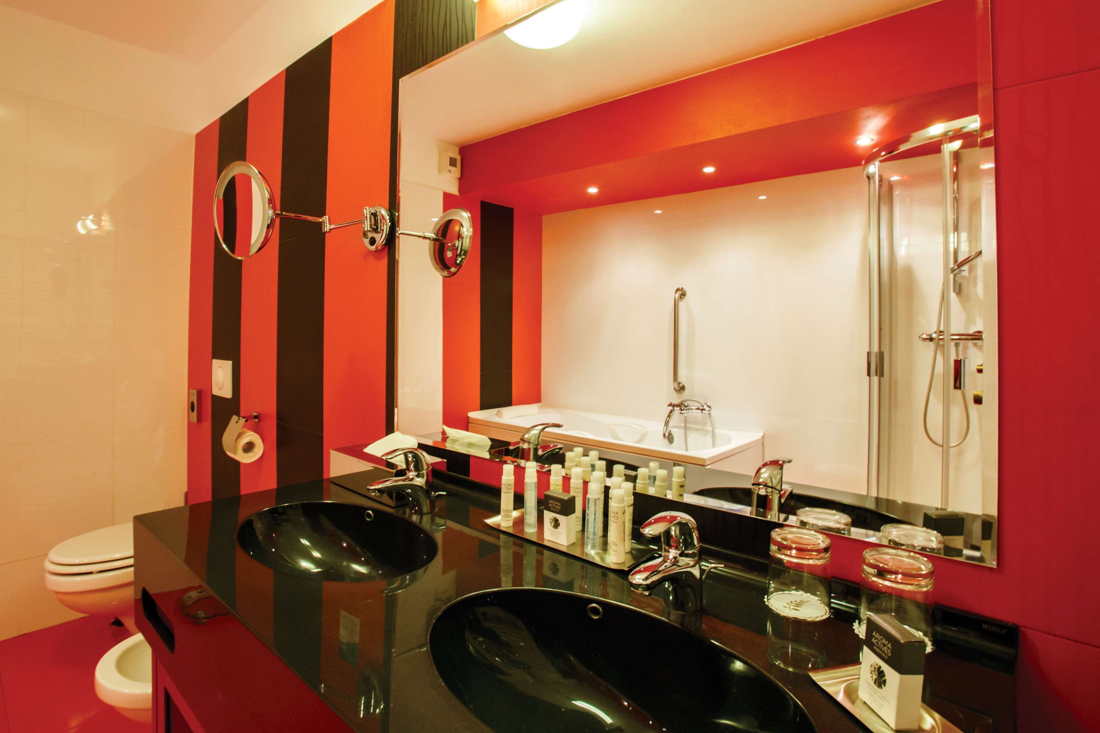 Une salle de bain moderne avec un lavabo noir, des toilettes blanches et une douche à parois de verre.