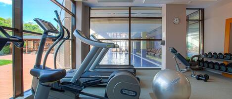 Un gimnasio con cintas de correr, una pelota de ejercicio y pesas.