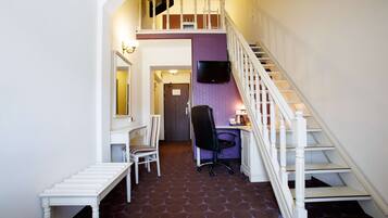 A staircase with a white railing leading to a second floor, a desk with a chair, and a television mounted on the wall.