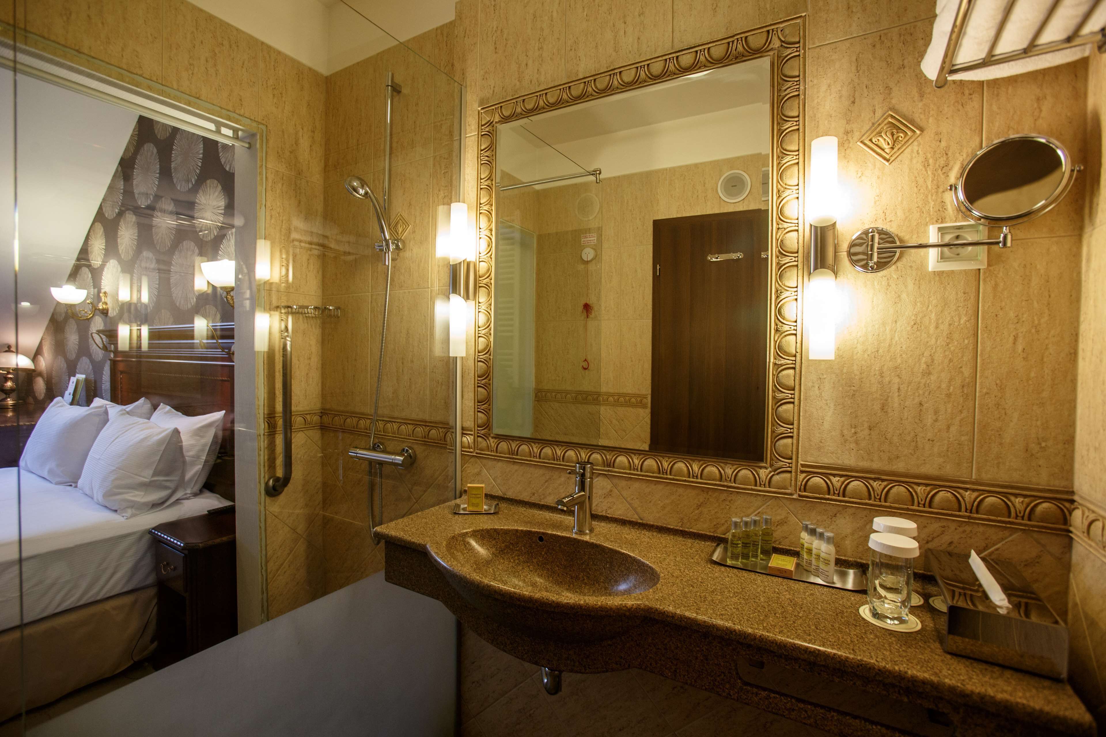 A hotel bathroom with a large mirror, a sink, and a shower.