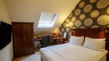 A bedroom with a large bed, a desk, a wardrobe, and a skylight.