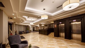 Un vestíbulo amplio con piso a cuadros, muebles modernos y una recepción.