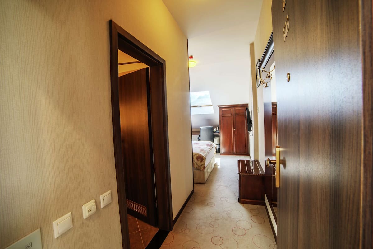 Een hotelgang met een houten deur, een bed en een kleine keukenhoek.