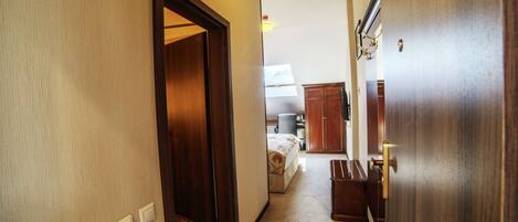 Un pasillo de hotel con una puerta de madera, una cama y una pequeña zona de kitchenette.