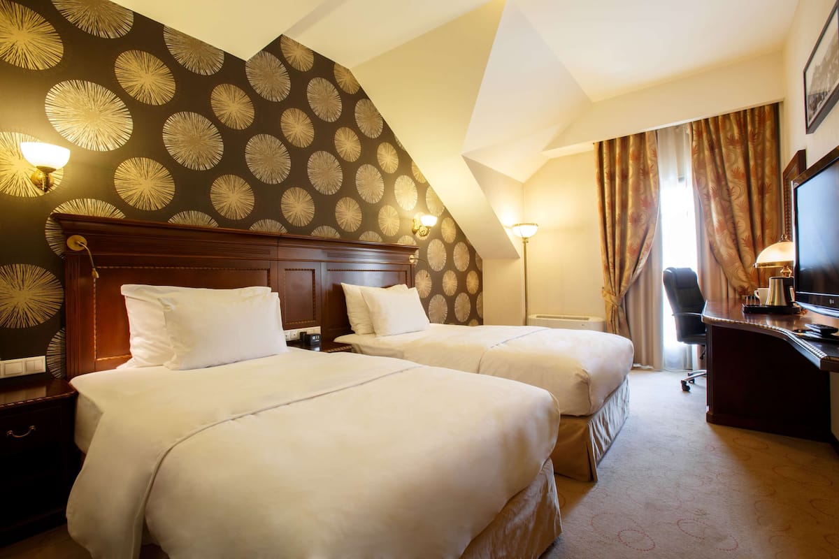 Een hotelkamer met twee bedden, een bureau, een stoel, een televisie en een lamp.
