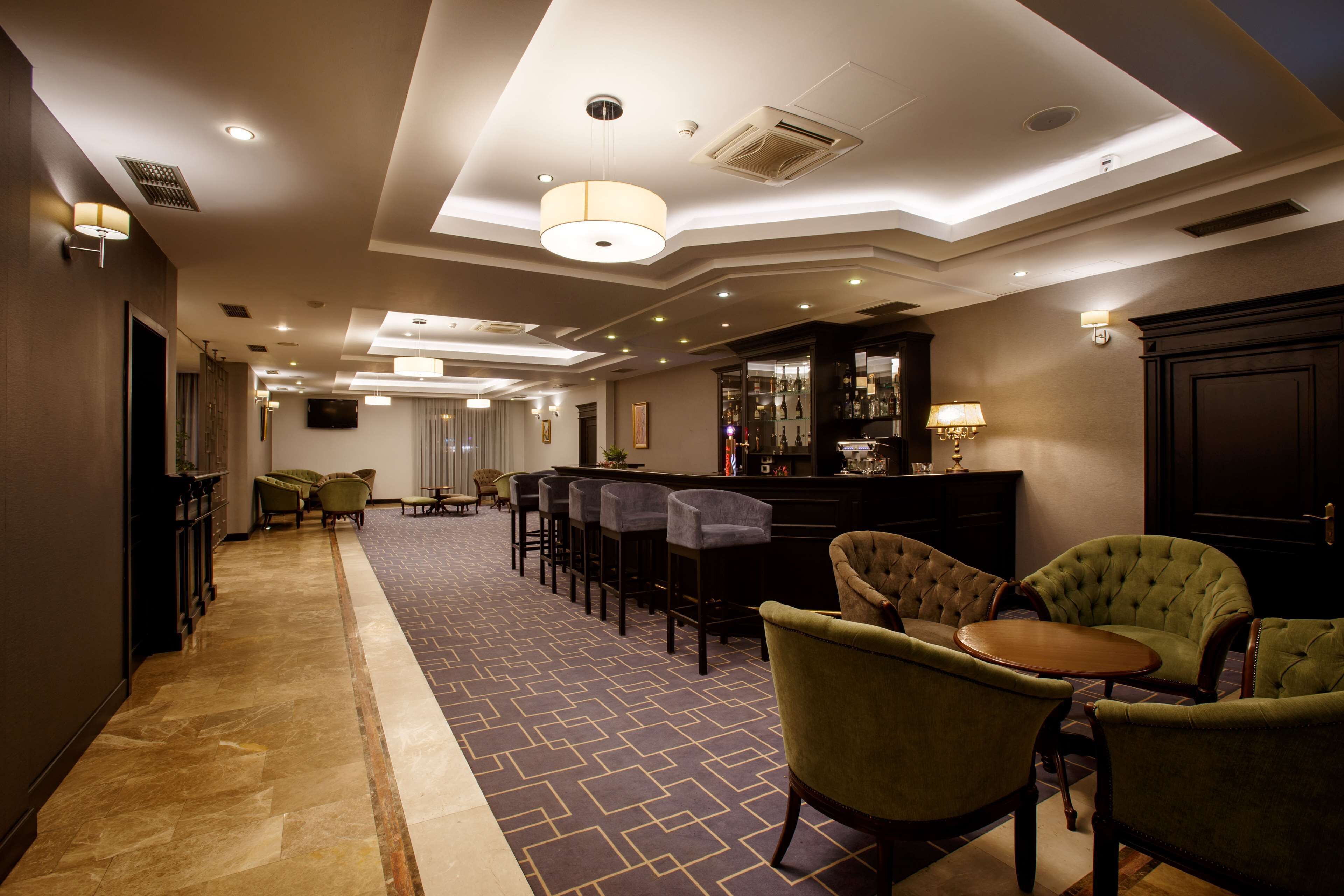 Hall d'albergo con area bar, posti a sedere e tappeto decorato.