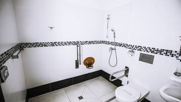 Un baño con inodoro blanco, lavabo y zona de ducha.
