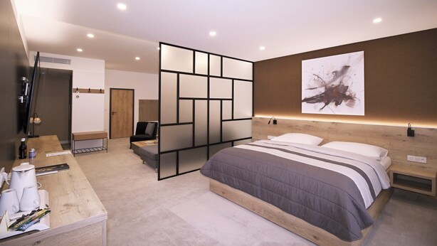 Une chambre à coucher moderne, avec un lit, des tables de chevet, un bureau et un grand tableau abstrait accroché au mur.
