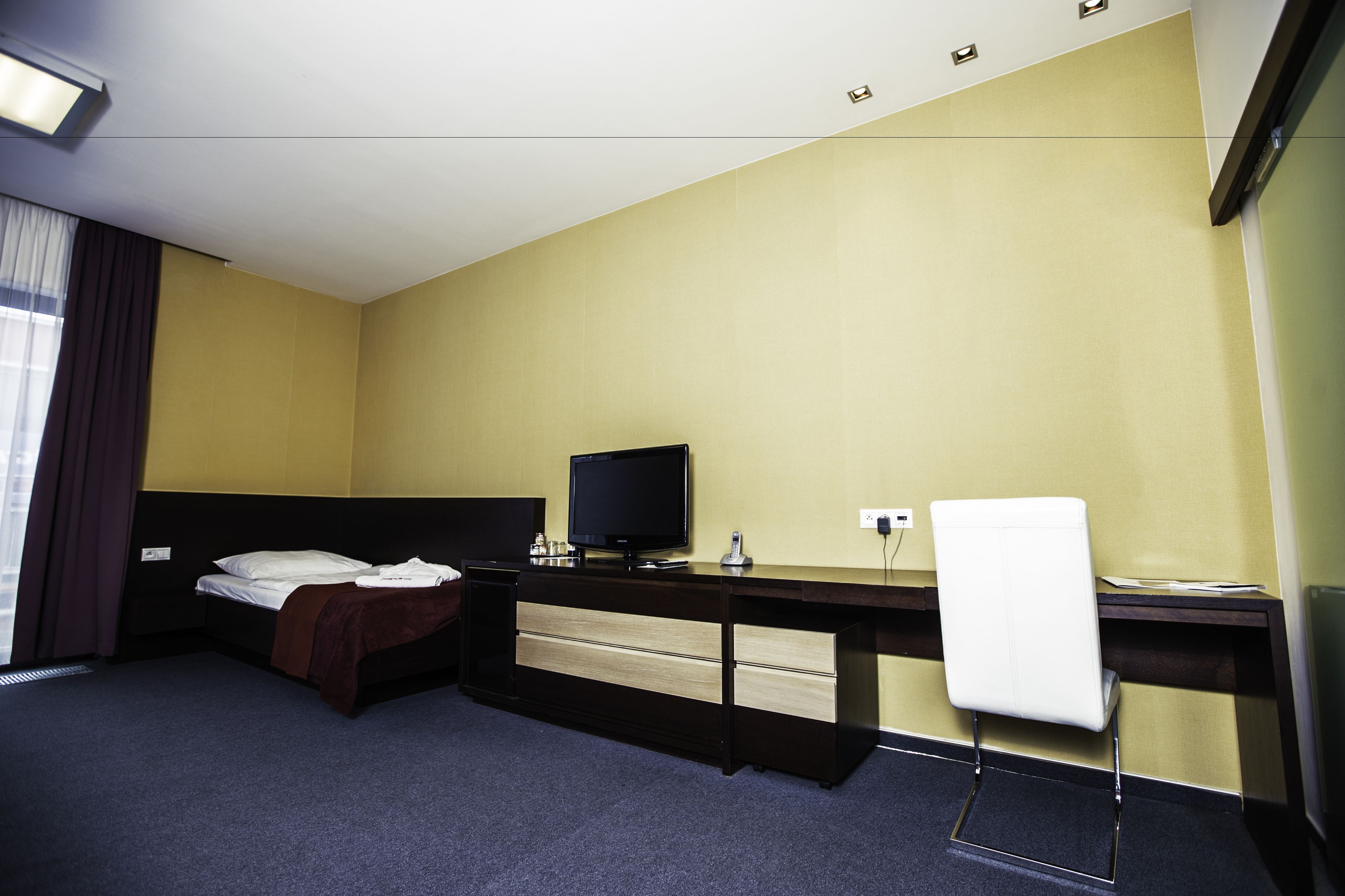 Una habitación de hotel con cama, escritorio, computadora y una silla.