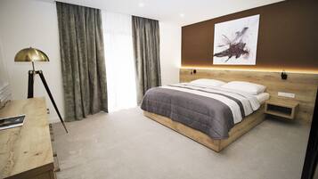 A modern hotel room with a wooden bed, a desk, and a large window with curtains.