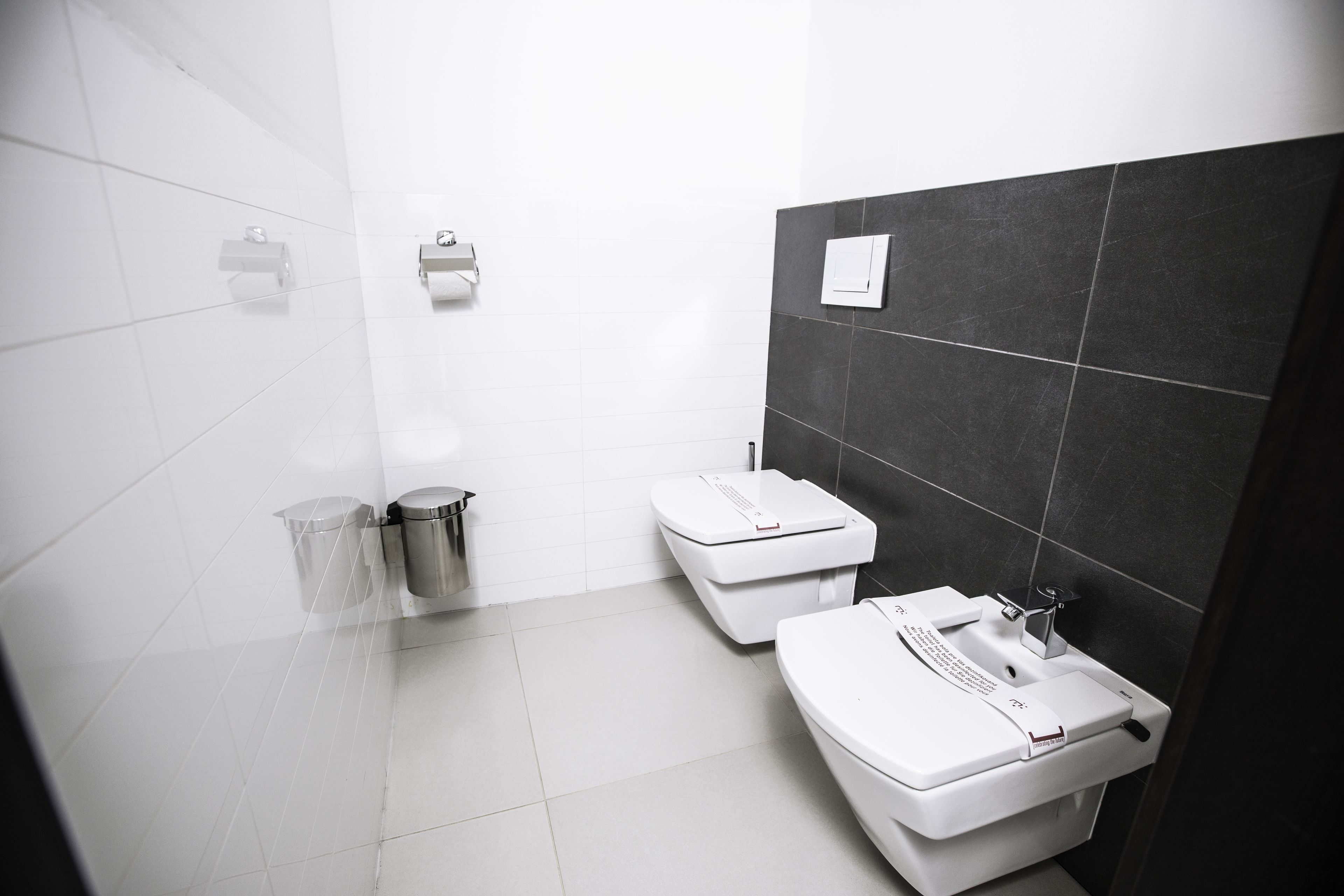 Een moderne badkamer met een wit toilet, een wastafel en een prullenbak.
