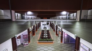 Un vaste couloir doté d’un espace de repos central, bordé de panneaux de verre et de rampes métalliques.