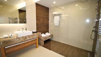 A modern bathroom with a large mirror, a sink, a shower, and a bench.