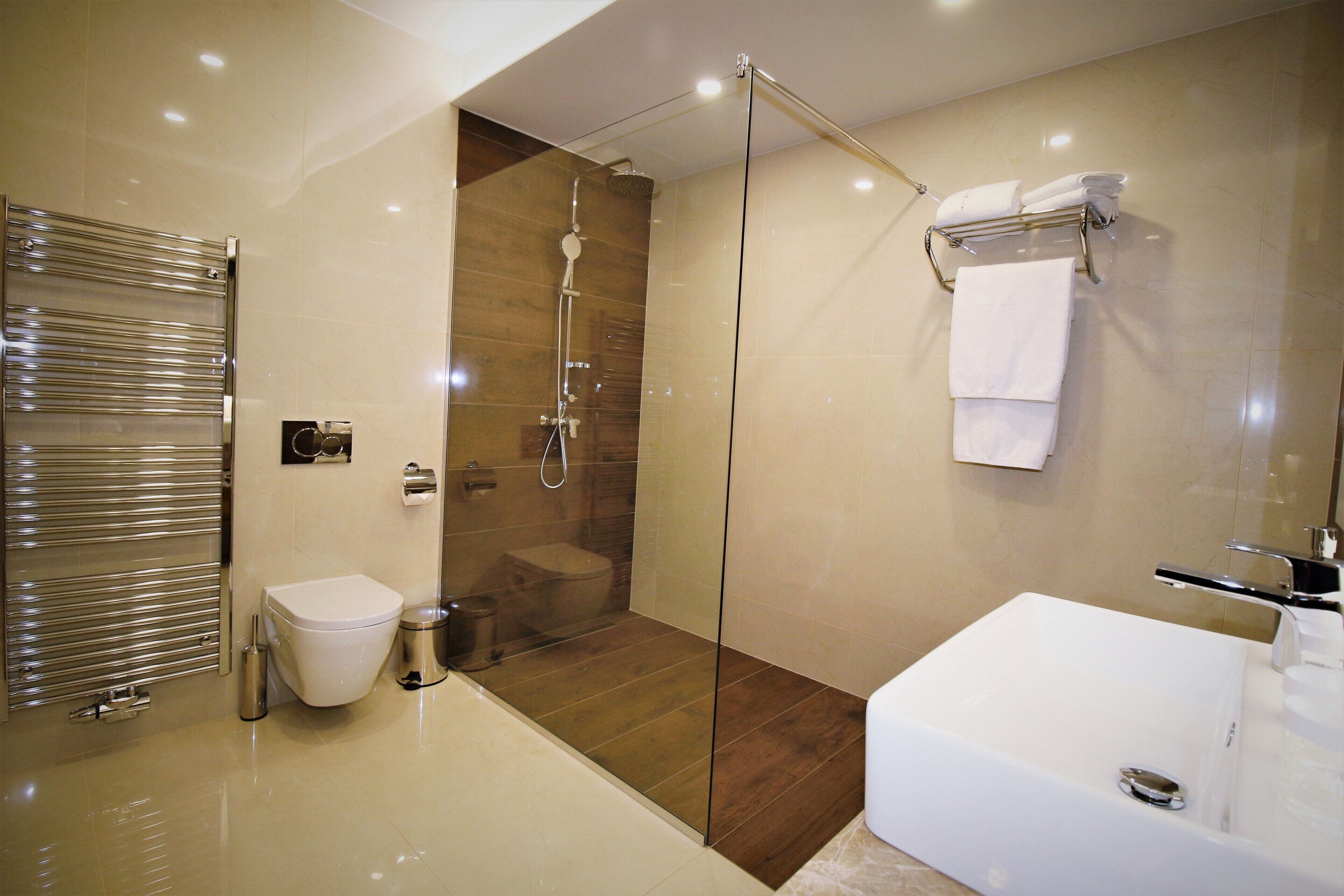 A modern bathroom with a glass-enclosed shower, a white toilet, and a large bathtub.