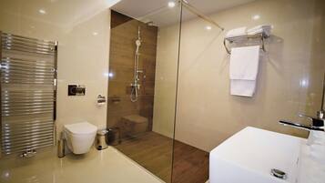 A modern bathroom with a glass-enclosed shower, a white toilet, and a large bathtub.