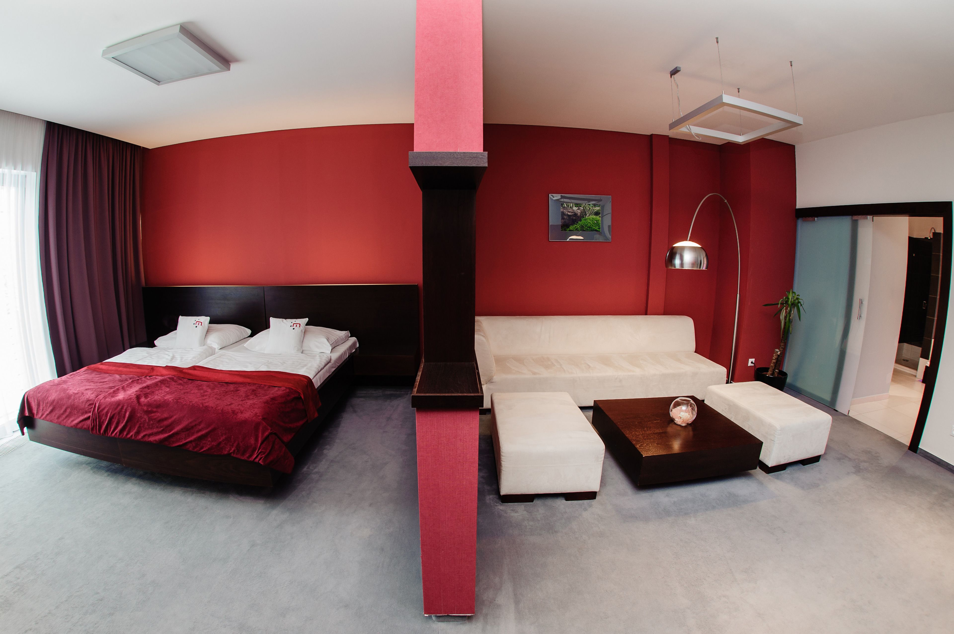 Una habitación de hotel moderna con una cama grande, un sofá blanco y una pequeña mesa.