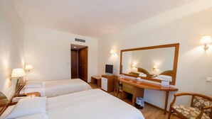 Habitación de hotel con dos camas individuales, un escritorio con computadora, una silla y un espejo grande.