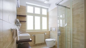Un baño moderno con cabina de ducha de vidrio, inodoro, lavamanos y ventana.